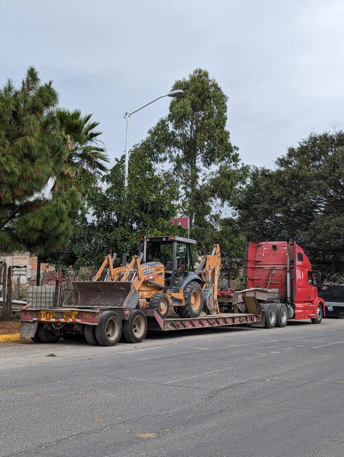 Retroexcavadora CASE transportada en cama baja por el flete propio de Paredes